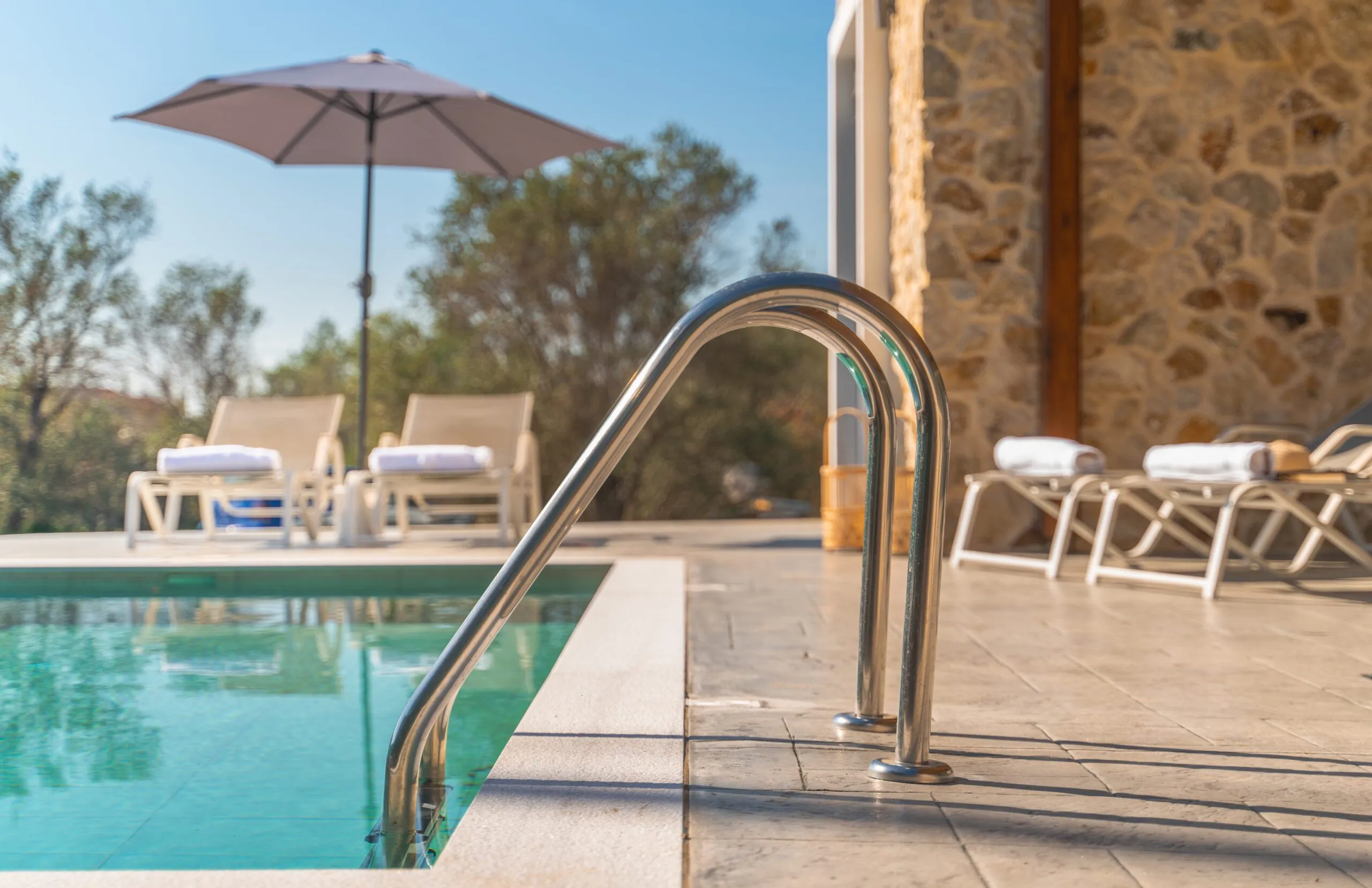 Pool ladder with loungers and umbrella