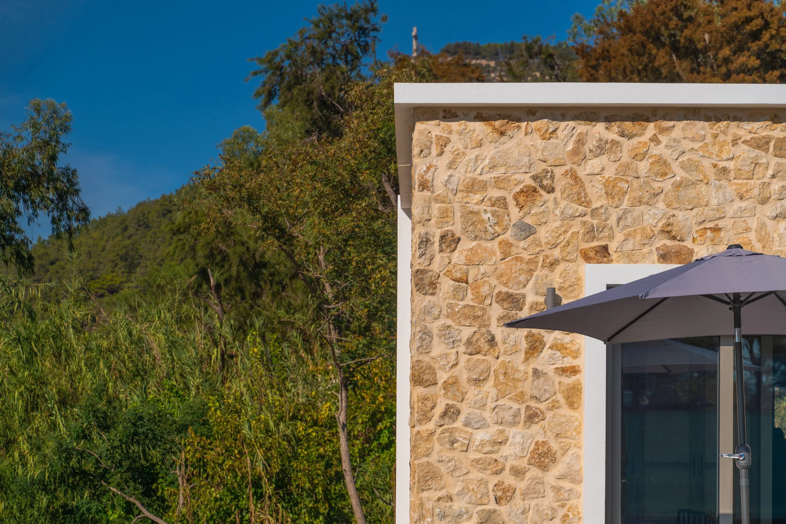Stone wall of the villa among the trees