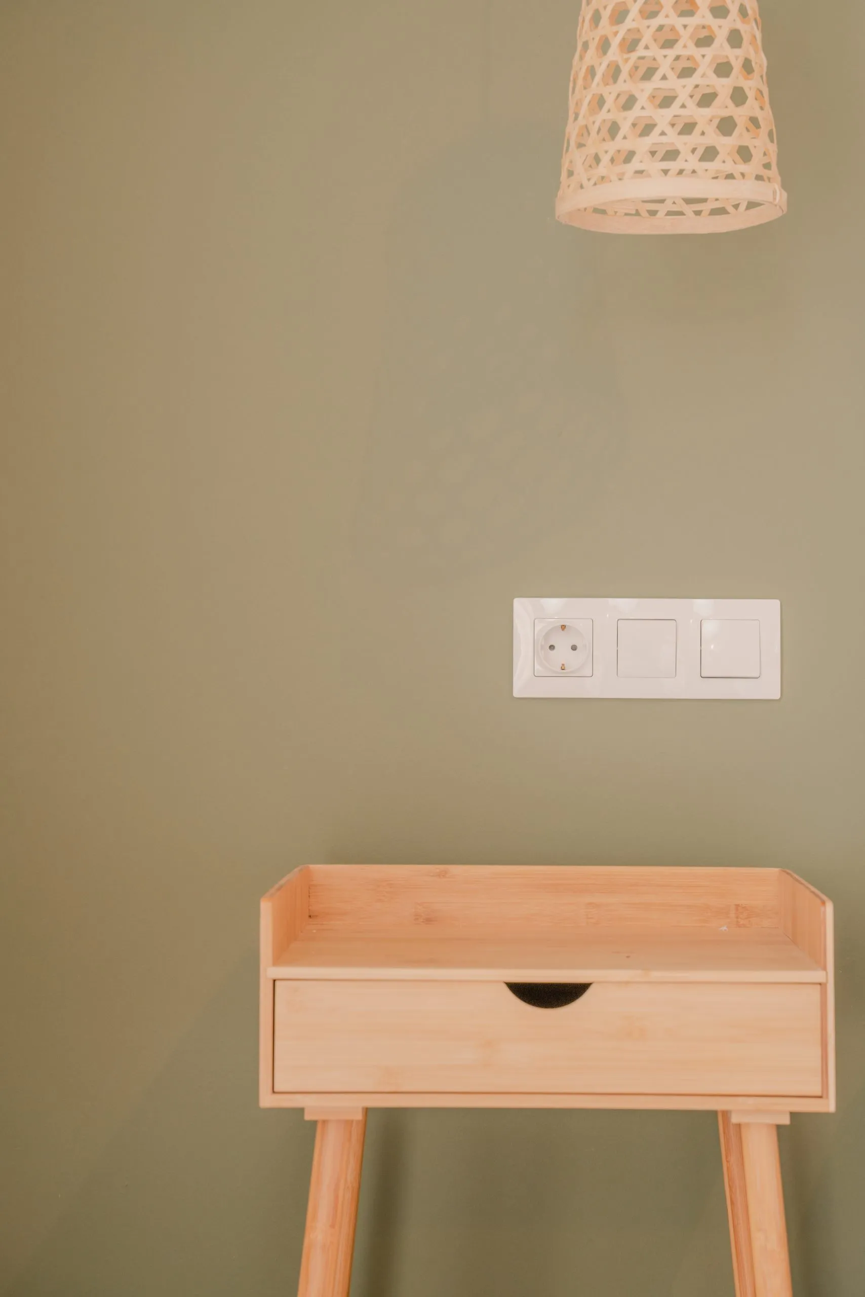 Bedside table against a sage green wall